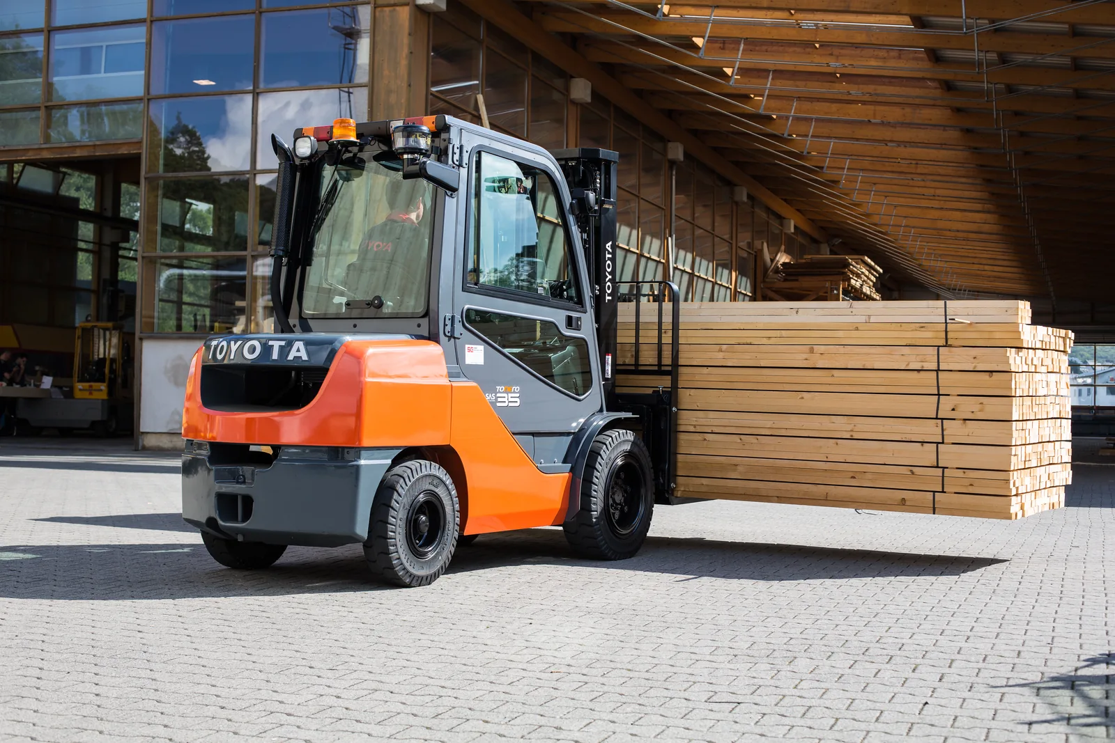 Toyota Tonero Gabelstapler transportiert ein großes Holzpaket über den Hof eines Holzhandels