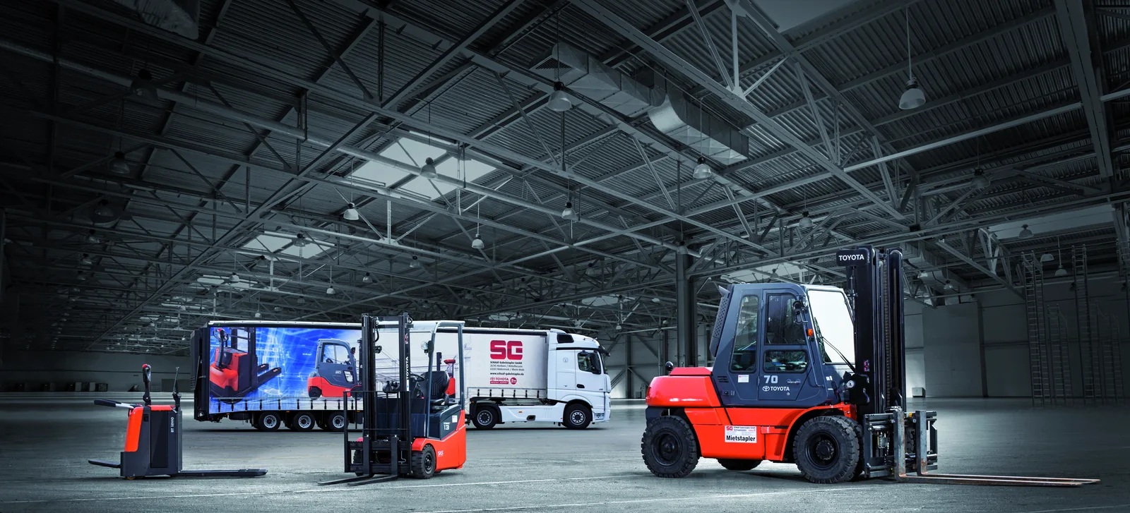 Neugeräte von Schaaf in der Halle: Elektro-Hubwagen, Toyota-Frontstapler und Schwerlaststapler vor dem Schaaf-Lkw